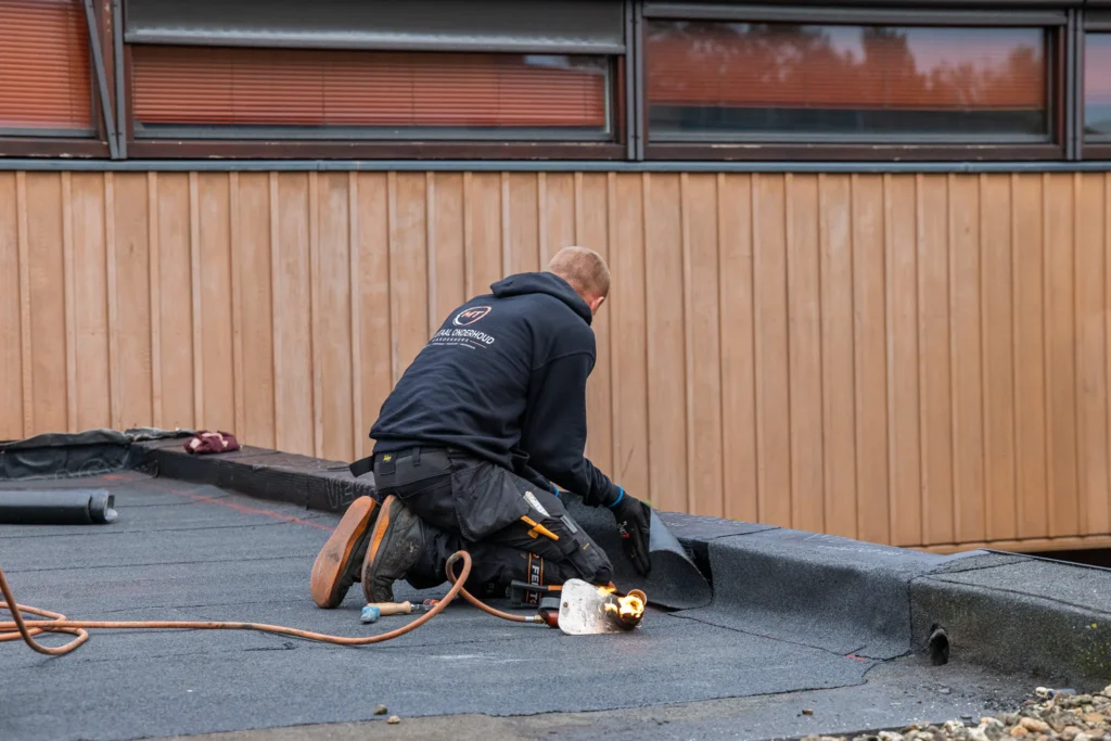 Dakdekker van MT Totaalonderhoud brandt de dakbedekking aan langs de dakrand in Amsterdam